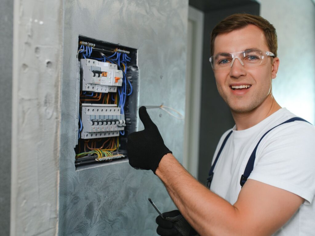 an electrician holding a thumbs up after upgrading an electrical panel
