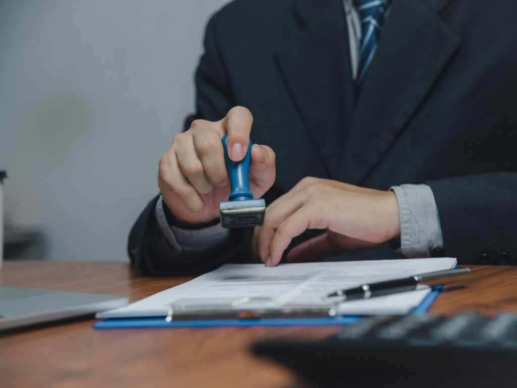 person in a suit at a desk stamping an electrical permit